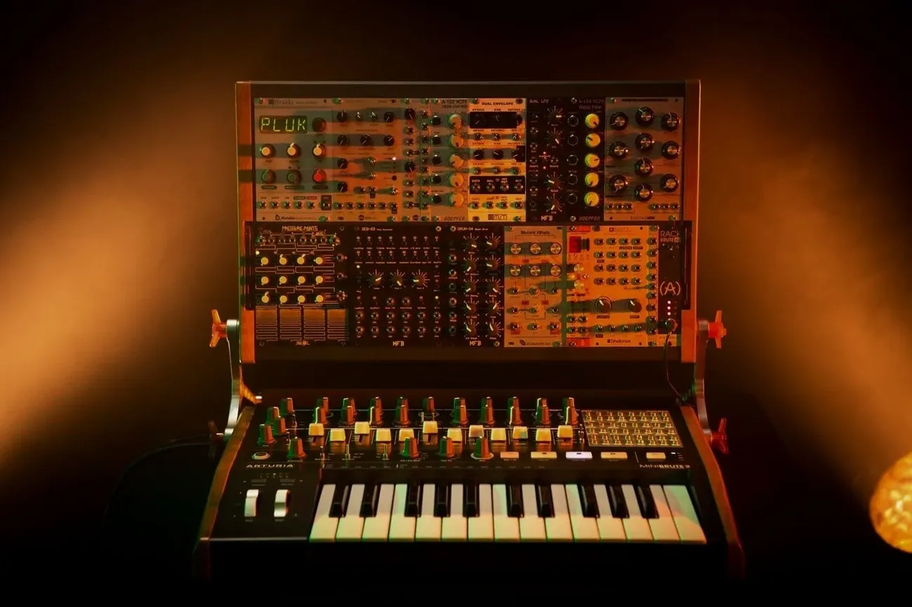 Analog bass synthesizer setup with modular hardware and keyboard controller under warm lighting
