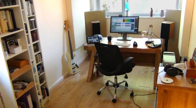 Home studio setup with computer, speakers, guitar, and audio equipment for mastering music.
