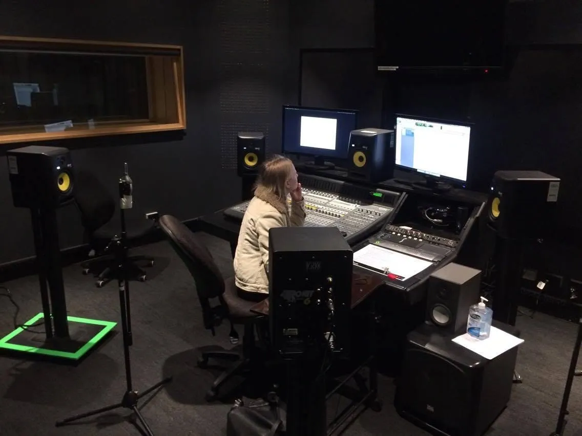 Person working on 5.1 surround sound mixing at an audio control console in a dimly lit studio room.